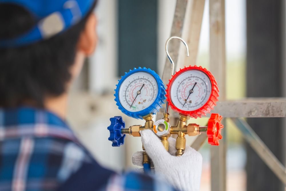 A man wearing a blue shirt and cap holds two gauges, illustrating HVAC repair services available in Honolulu, HI.